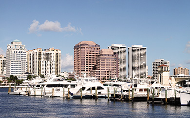 yachts in a peer with skyscrapers in the background in West Palm Beach